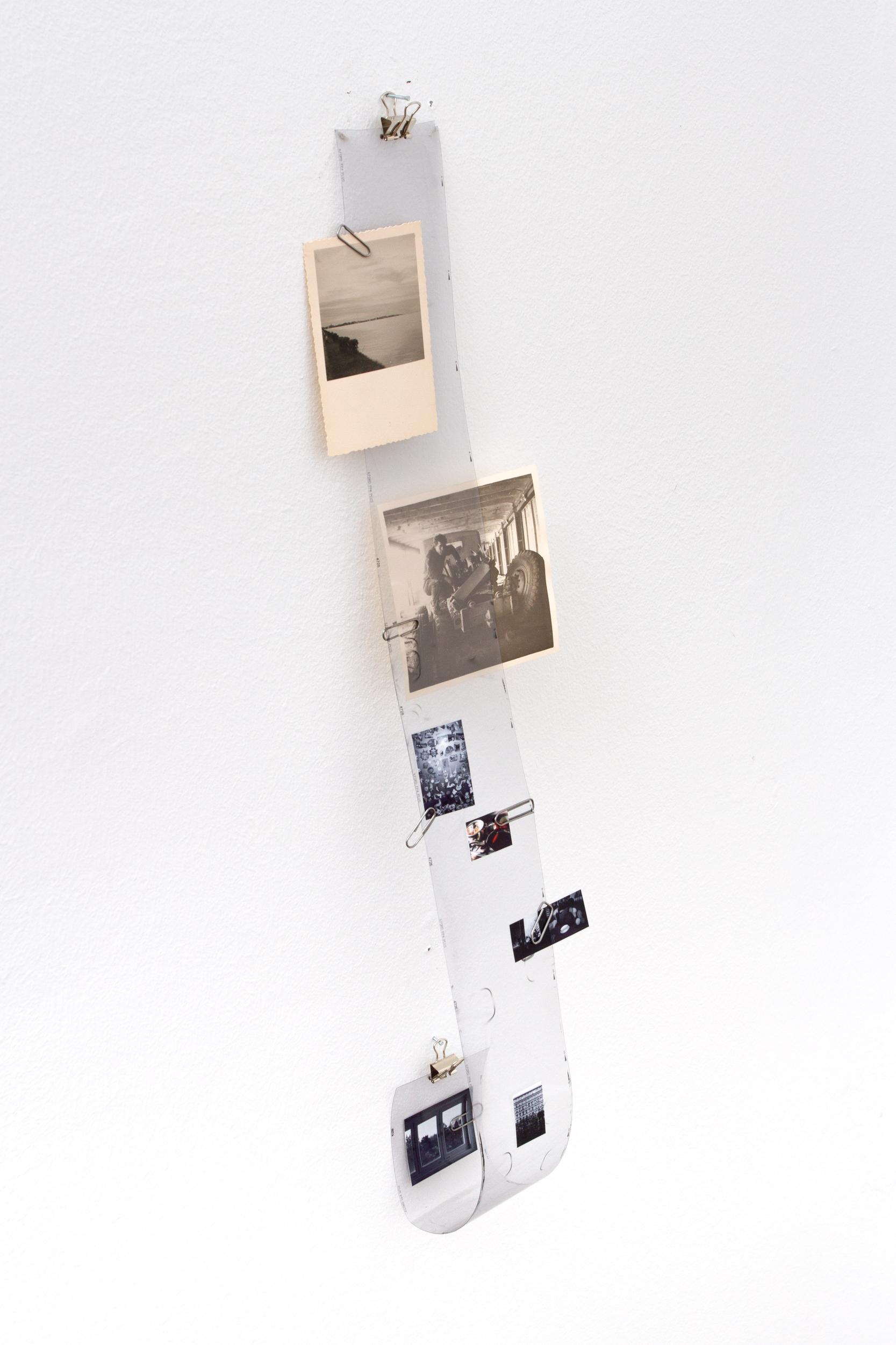 Untitled, 2026 – vertikal an der Wand montierter Filmstreifen mit angeklammerten Fotografien.